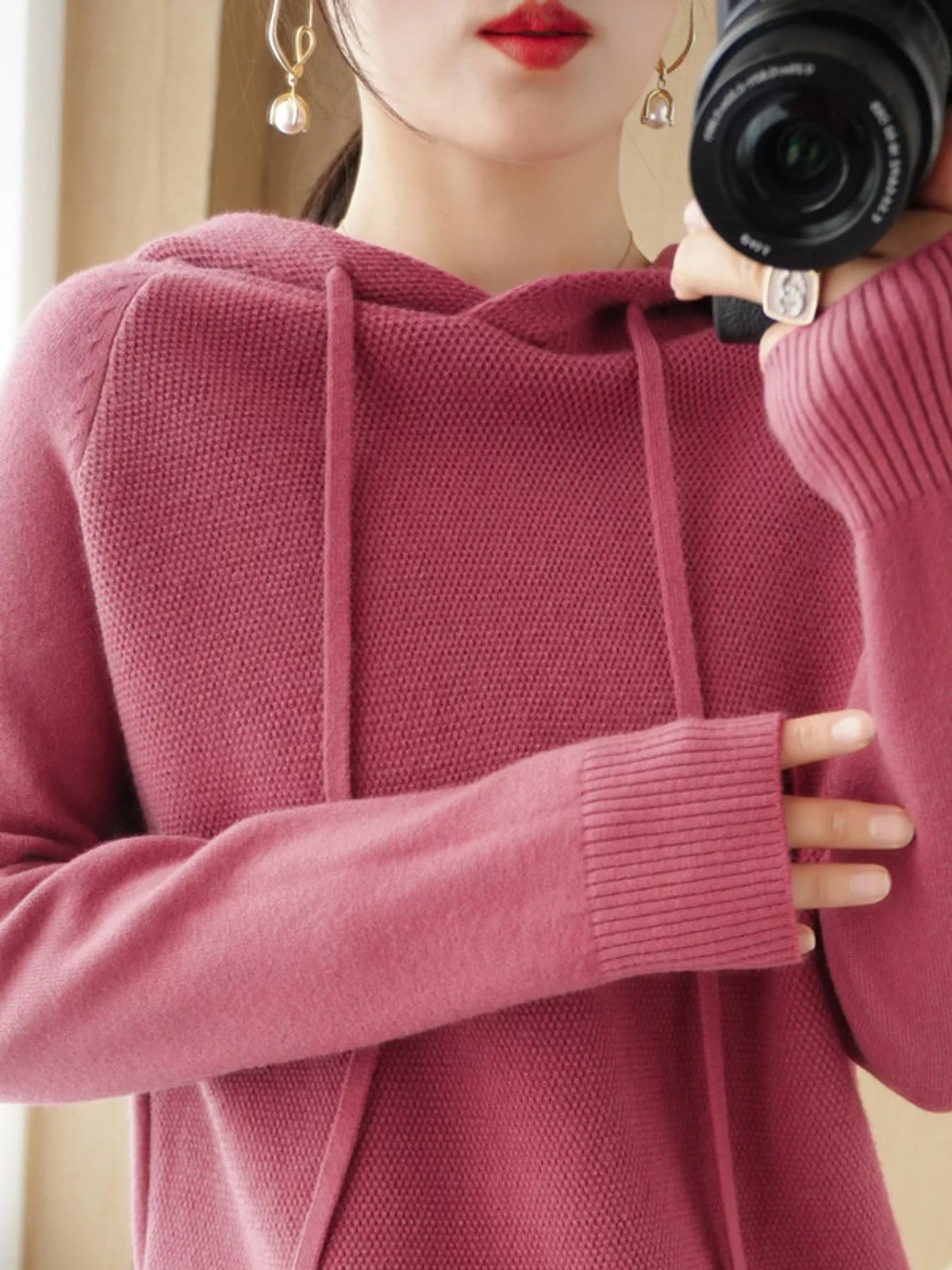 Dusty pink hooded sweater shown in a front mirror photo with one hand across the chest.