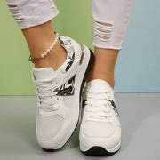 White floral sneakers shown from the front on feet
