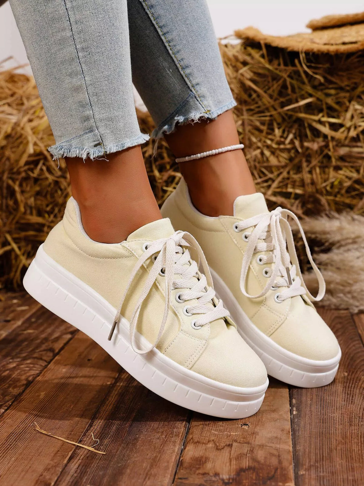White lace-up platform sneakers worn with jeans, angled view