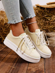 White lace-up platform sneakers worn with jeans, angled view