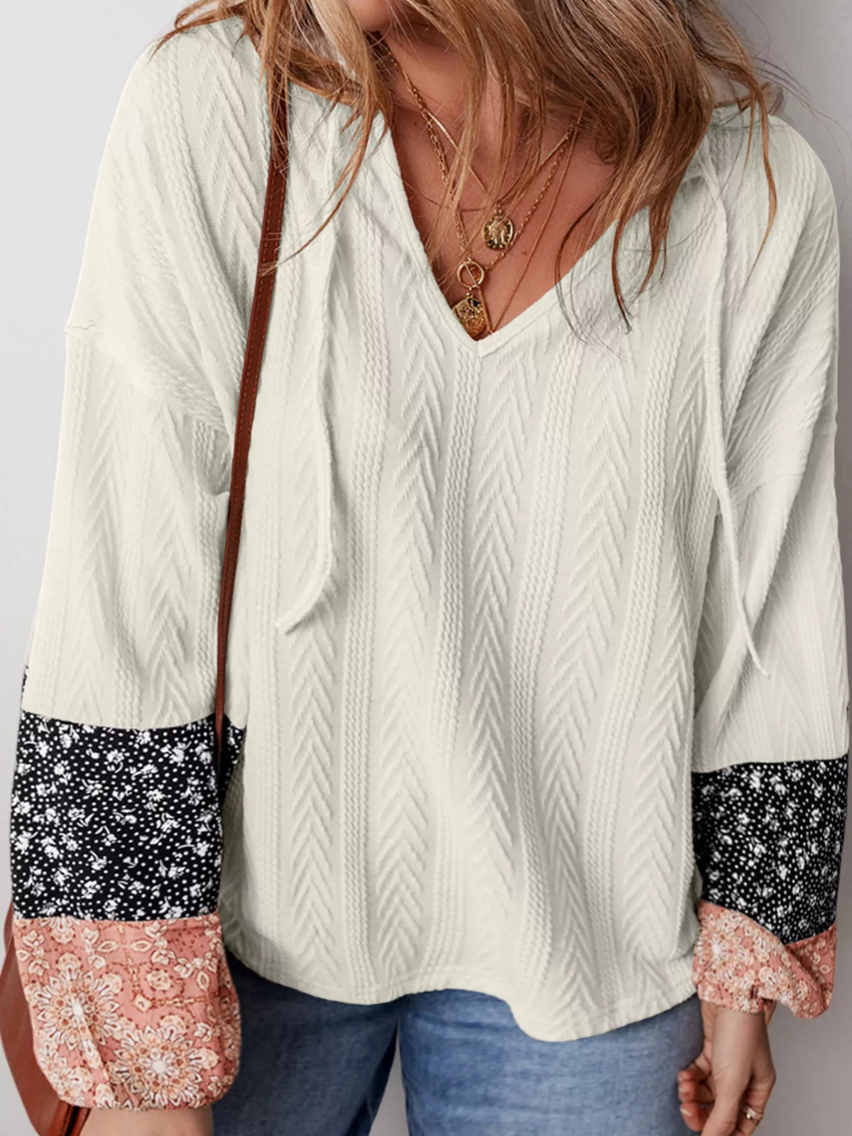Model wearing ivory textured V-neck blouse with patterned cuffs