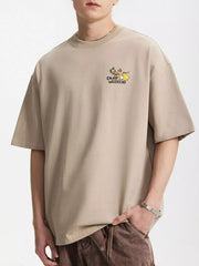 Model wearing beige T-shirt with small chest graphic