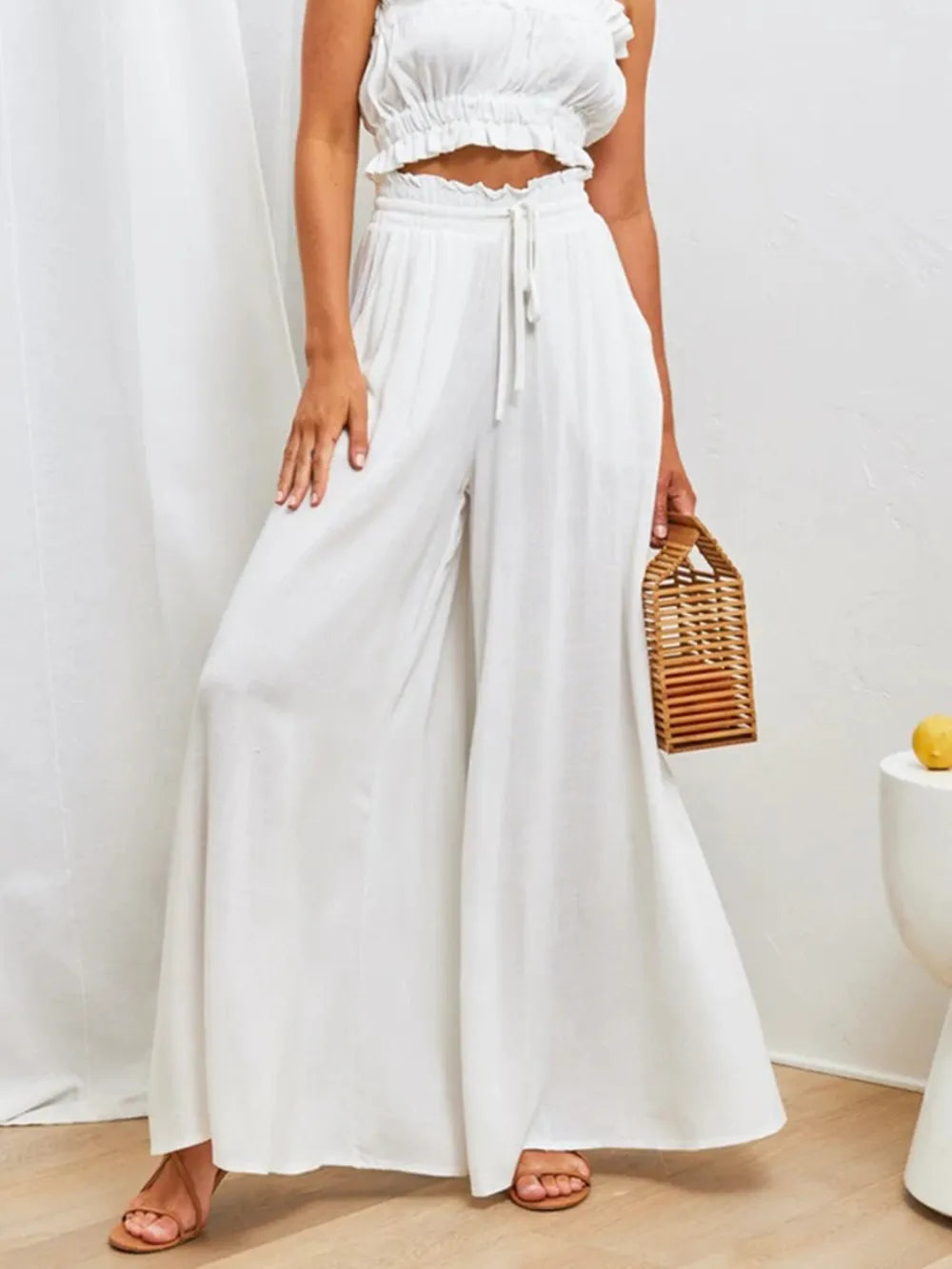 Model wearing white wide-leg pants with a cropped top