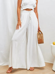 Model wearing white wide-leg pants with a cropped top