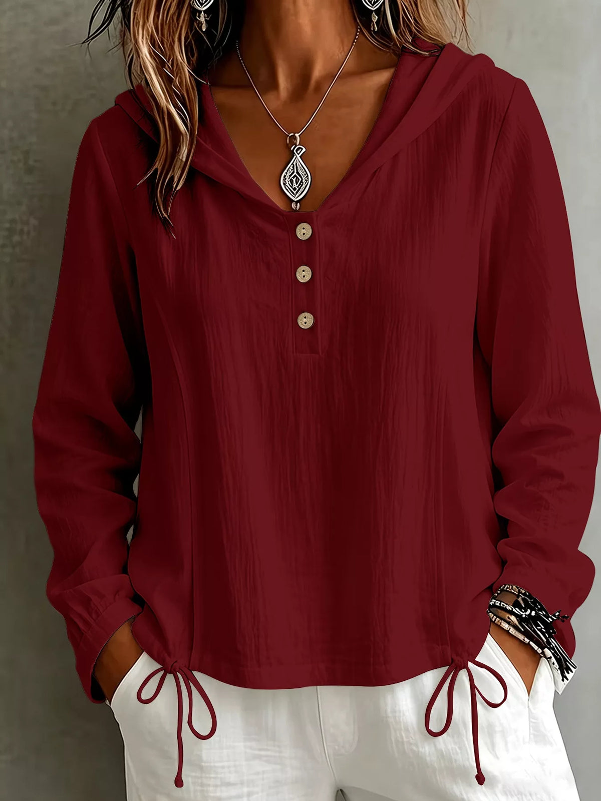 Front view of the burgundy hooded blouse with long sleeves and button placket.