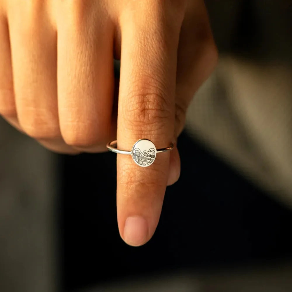 Engraved round face ring worn on finger, close-up