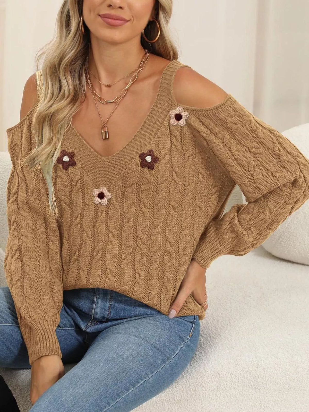 Tan floral-appliqué sweater shown in a seated pose