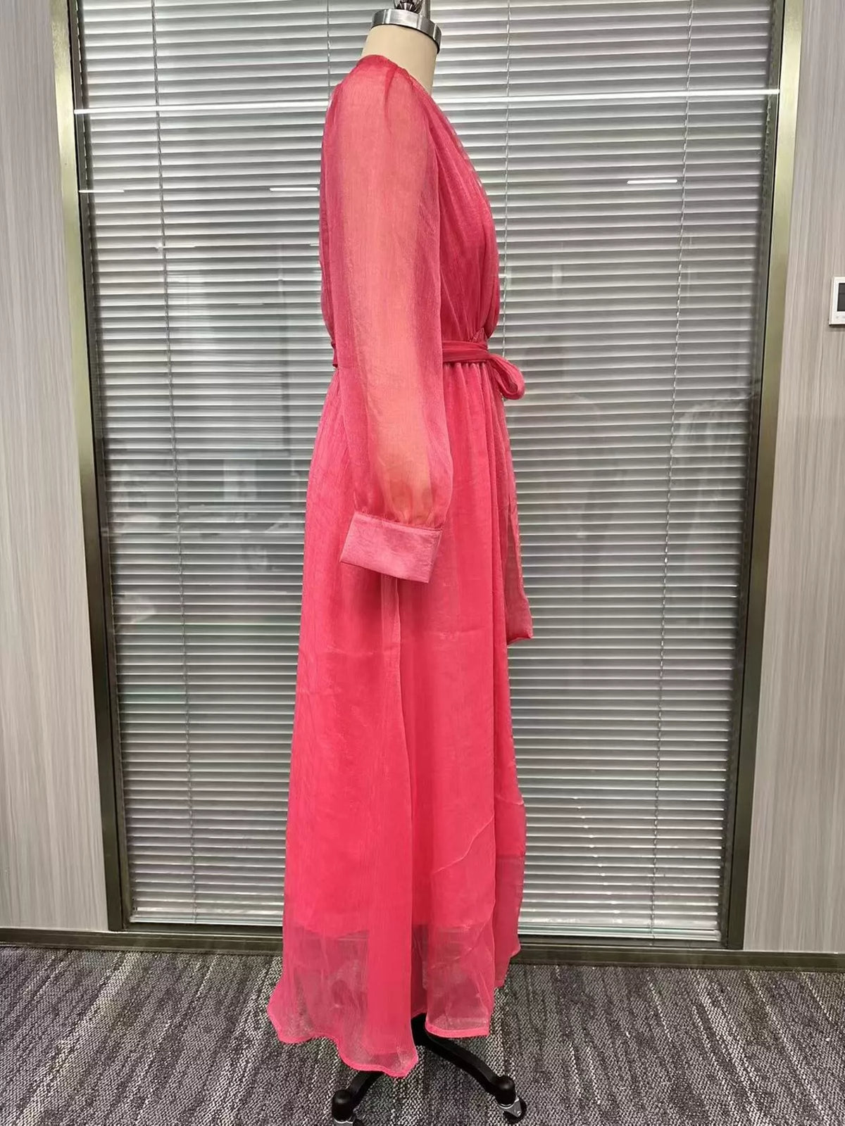 Side view of the pink wrap maxi dress on a dress form, showing the sleeve and layered skirt.