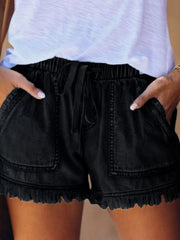 Black drawstring denim shorts with oversized front patch pockets and frayed hems