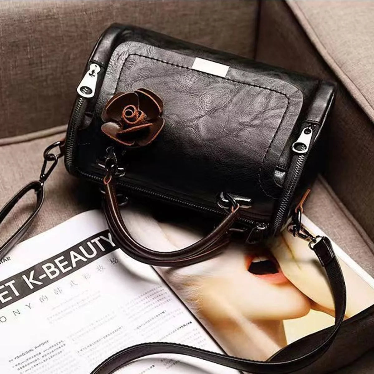 Black flap crossbody bag with flower ornament photographed from above