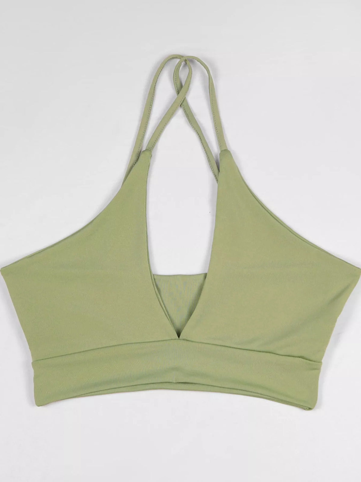 Light green halter crop cami displayed flat with crossed halter straps and front cutout