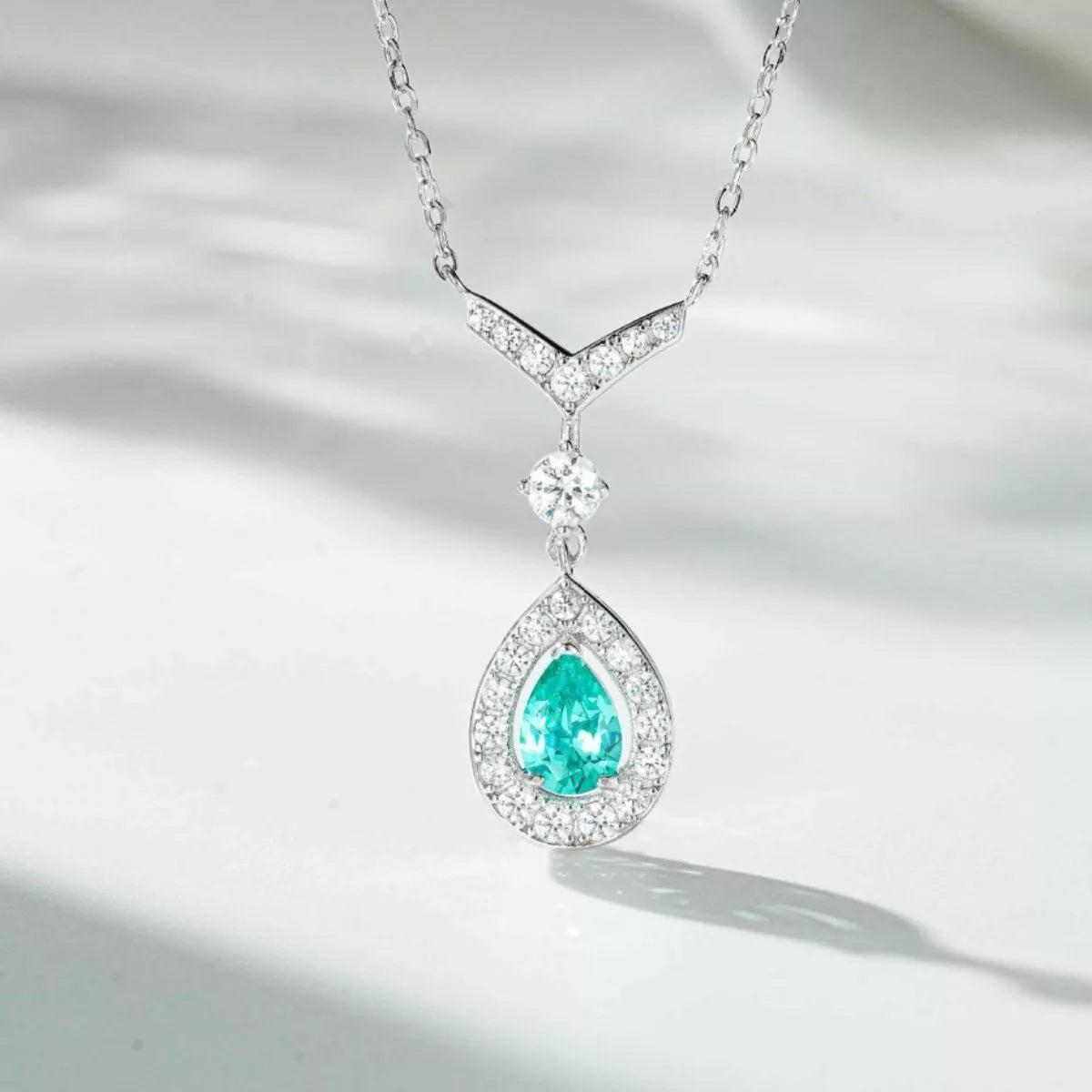 Light green teardrop pendant necklace arranged against a pale background
