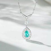 Light green teardrop pendant necklace arranged against a pale background