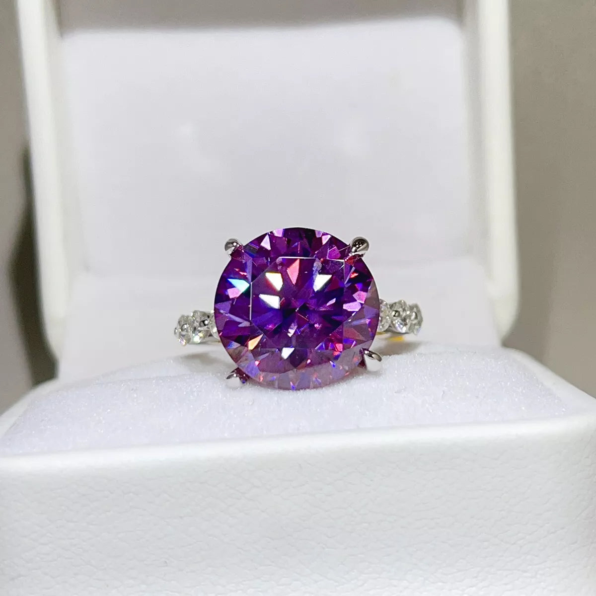 Purple round-stone ring displayed in a white jewellery box