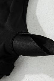 Close-up of the black swim dress strap hardware and gathered bodice seam.