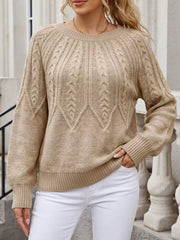 Front view of a beige cable-knit sweater with white trousers