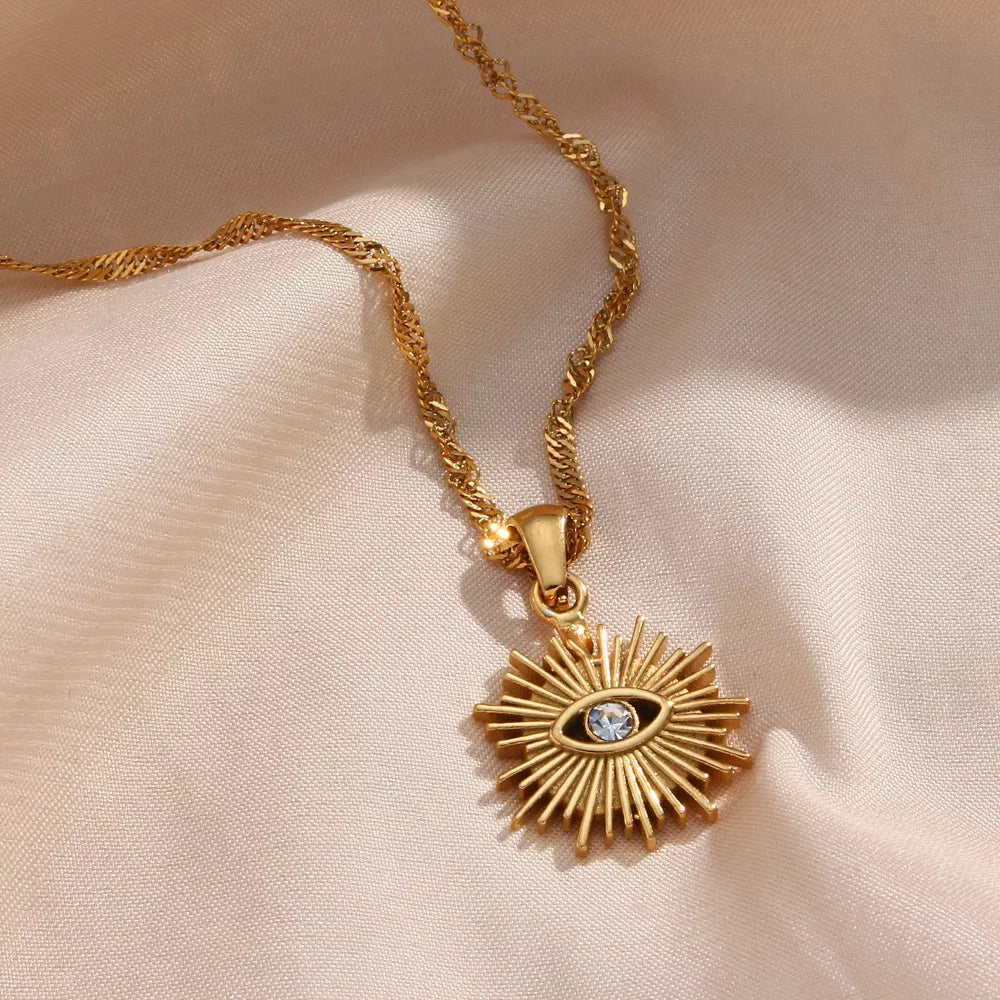 Close view of the necklace chain and gold-tone sunburst eye pendant