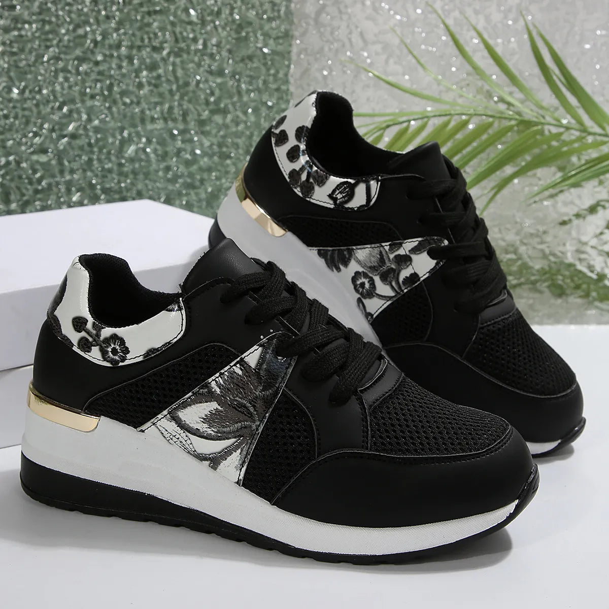 Pair of black sneakers with black-and-white floral panels, side view