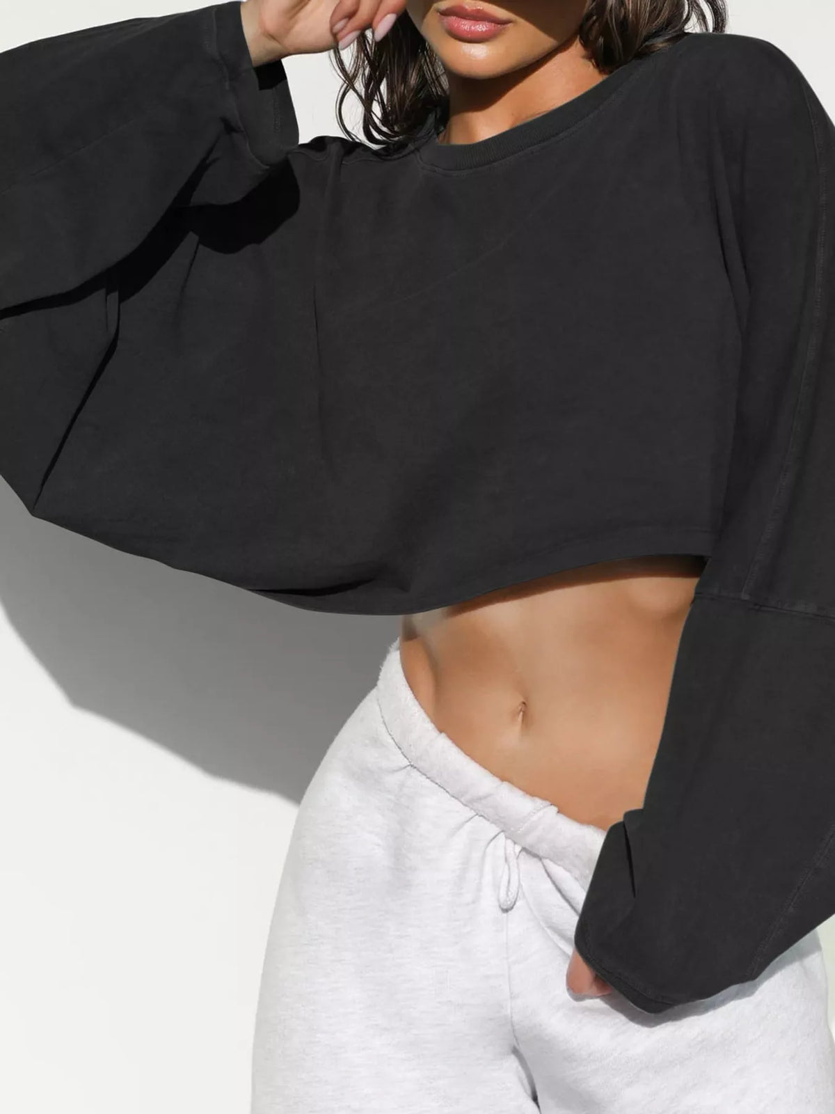 Angled front view of a black cropped sweatshirt with long sleeves.
