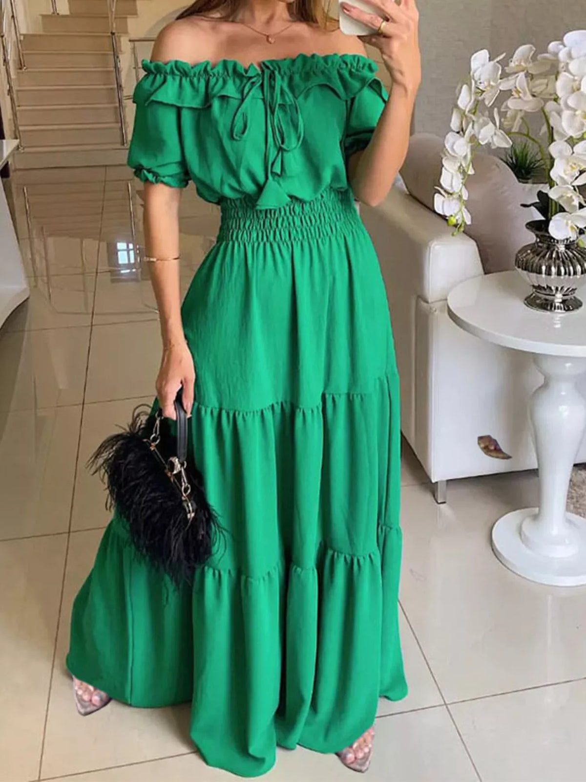 Model wearing a green off-shoulder tiered maxi dress with a ruffled neckline