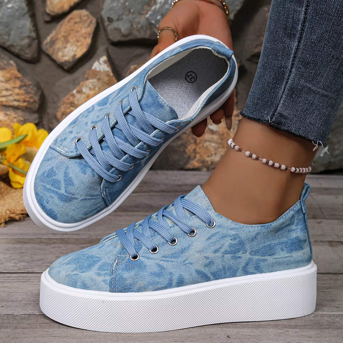 Blue patterned platform sneaker shown from the side with a second shoe held above