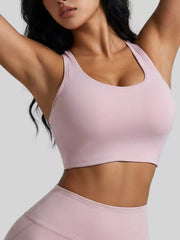 Pale pink scoop-front active bra shown with the model's arms raised.