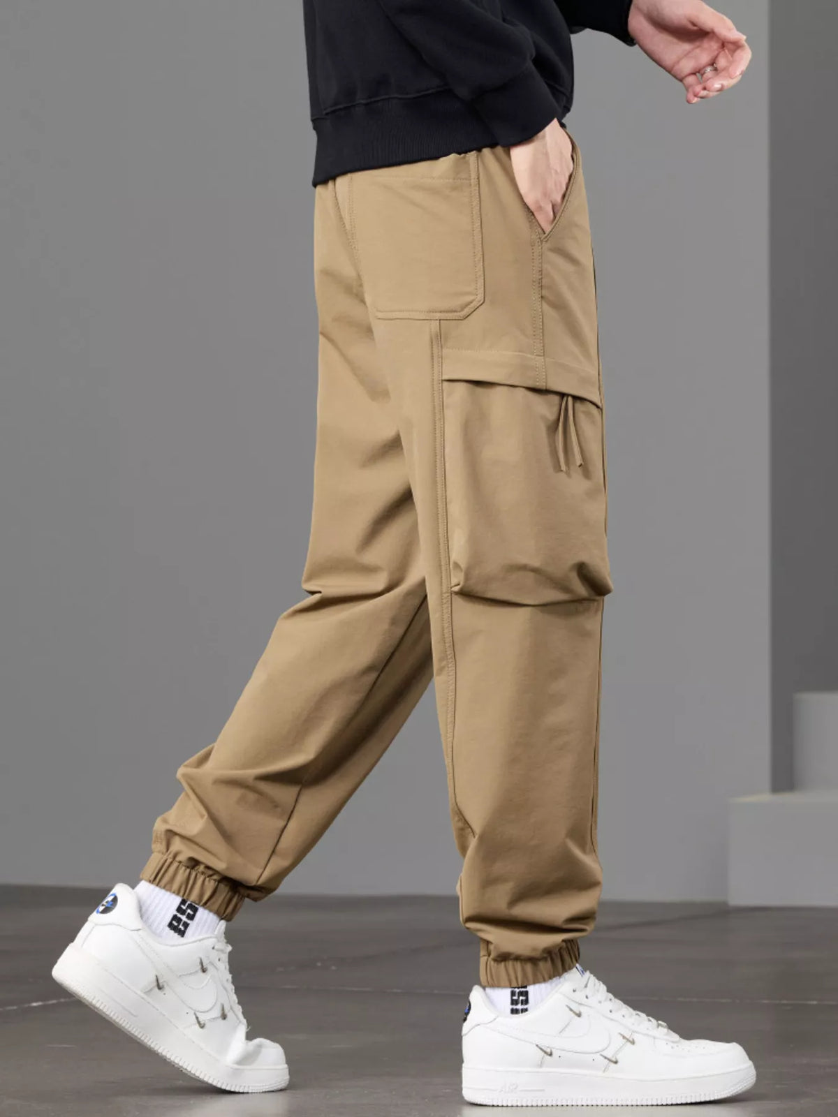Side view of tan cargo joggers highlighting the large flap thigh pocket.