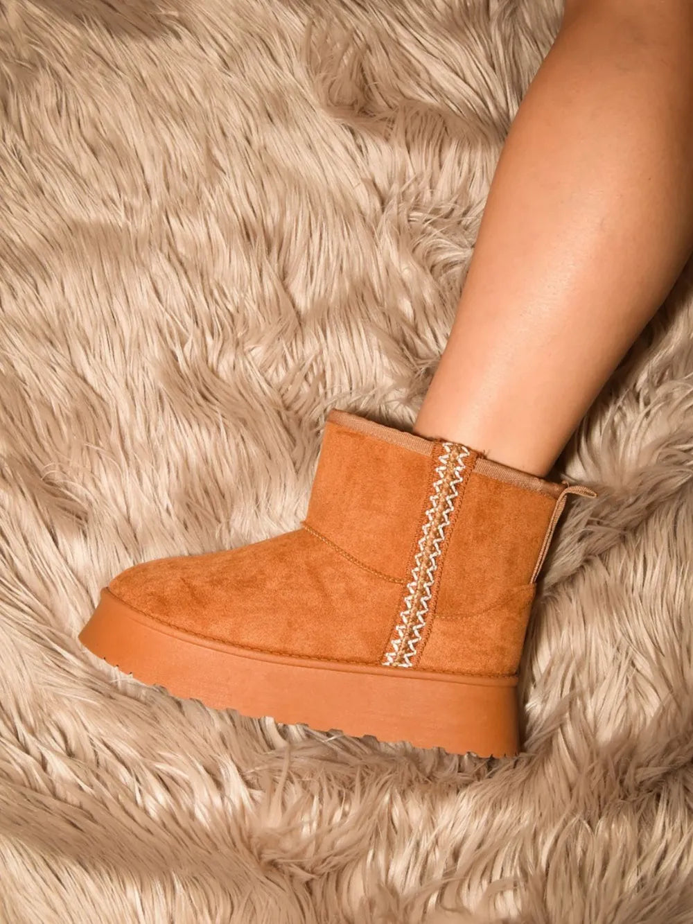 Tan round-toe platform ankle boot worn on foot against a textured rug
