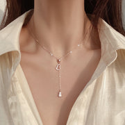 Rose-gold Y necklace worn with a pale blouse, showing its slim drop pendant