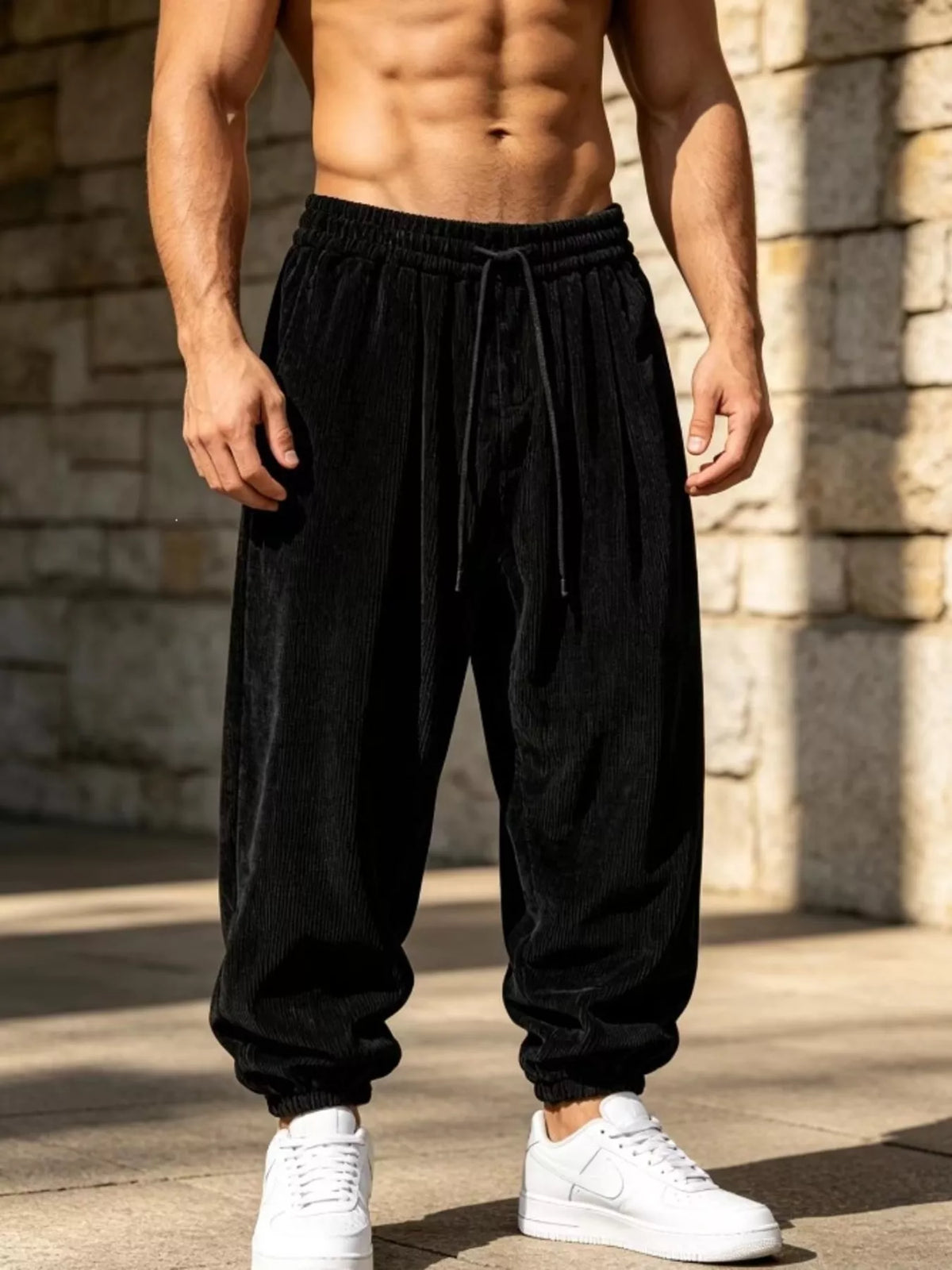 Black corduroy joggers with a gathered drawstring waist shown on a model