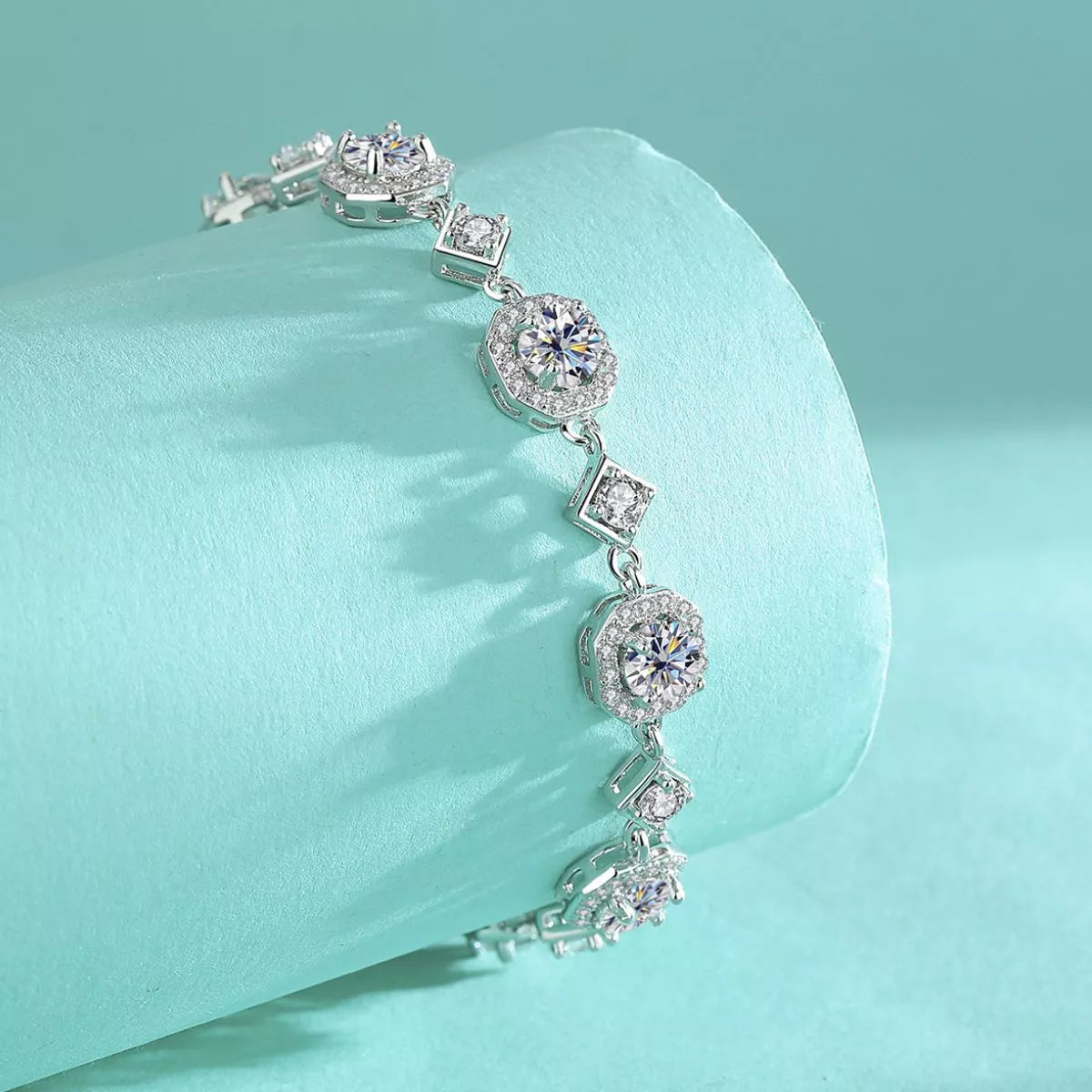 Side view of the silver-tone bracelet draped over turquoise fabric