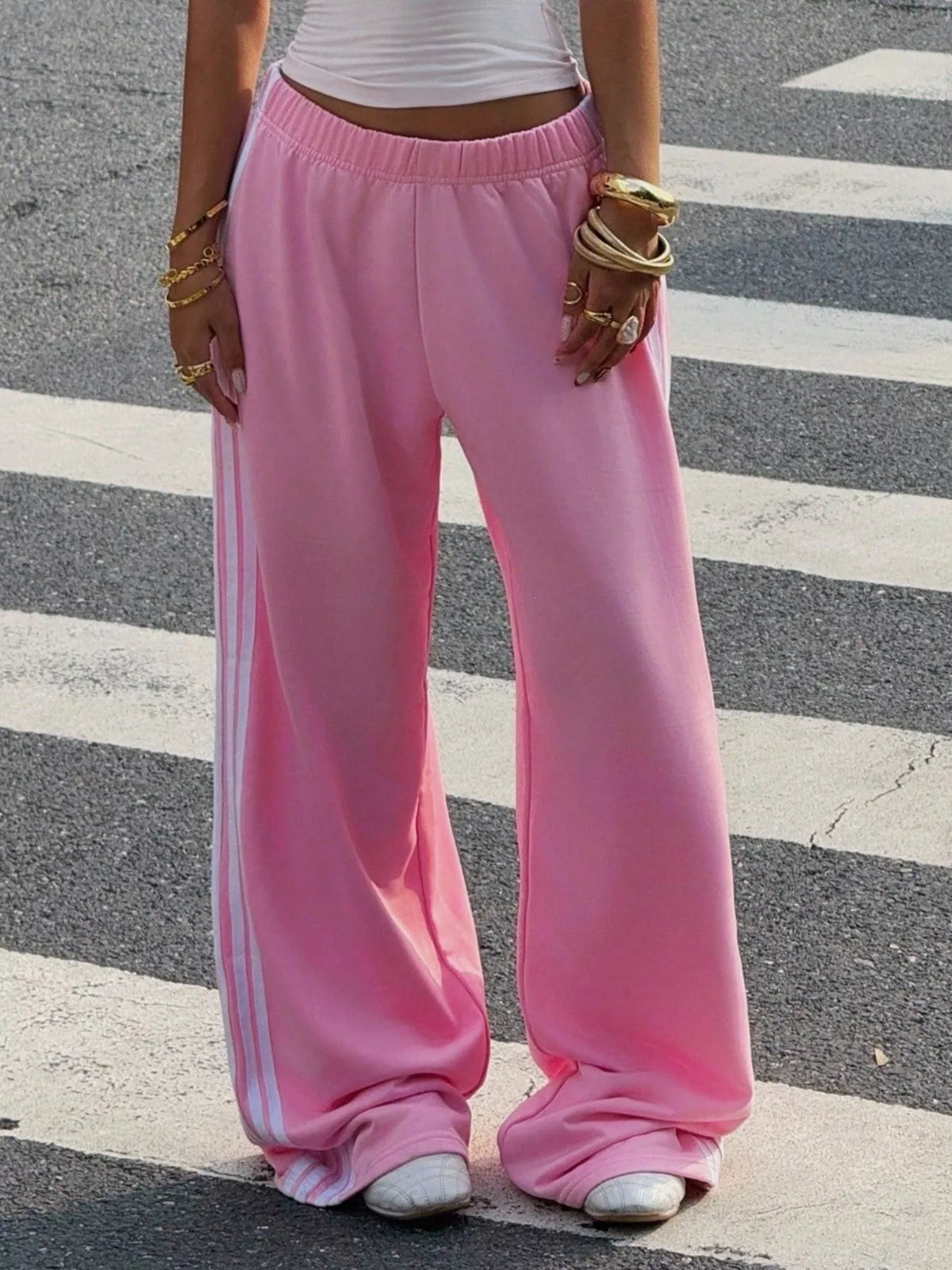 Pink striped track pants shown from the front with hands at sides