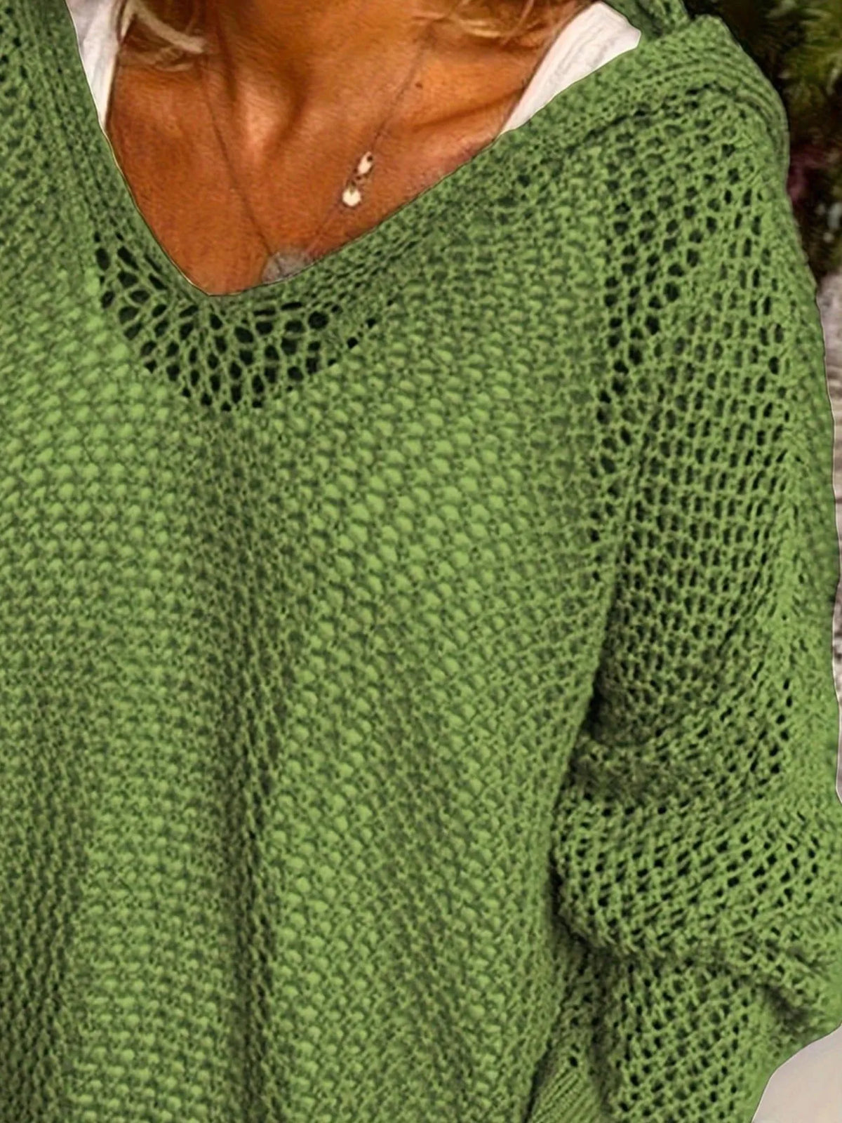 Close-up of the V-neck and open stitch pattern on a green knit cover-up.