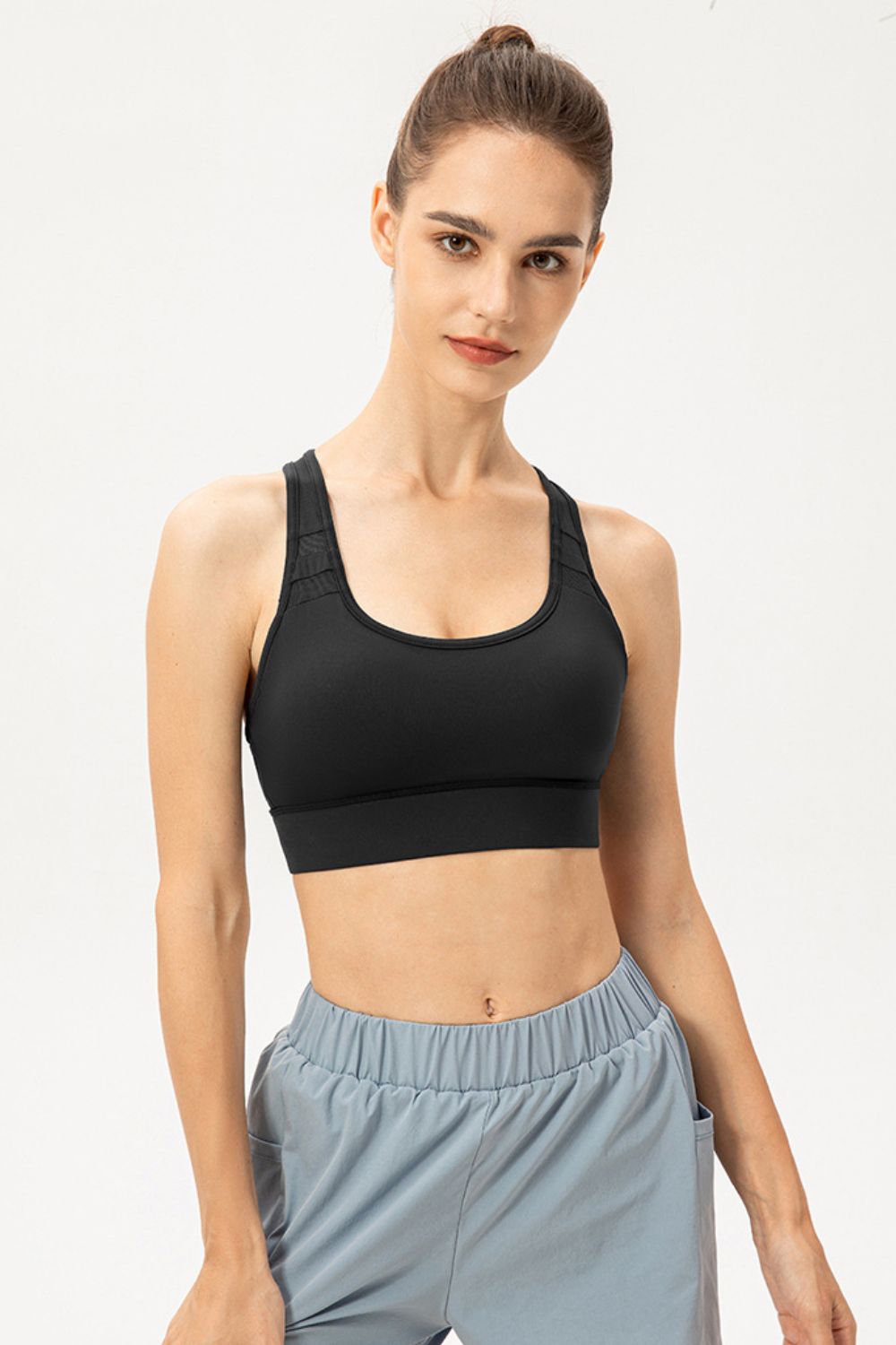 Model wearing black scoop-neck sports bra, front view