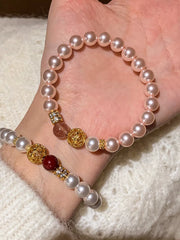 Pink pearl bracelet with gold filigree and burgundy accent beads worn beside a second bracelet