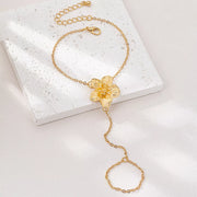 Gold-tone flower hand chain bracelet laid on a white jewelry box