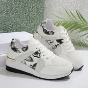 Pair of white sneakers with black floral panels and white soles
