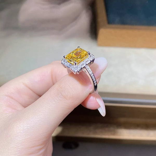 Yellow rectangular gemstone ring with clear accents held between fingers