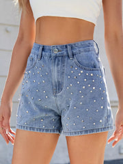 Front view of blue studded denim shorts with belt loops and a button waist