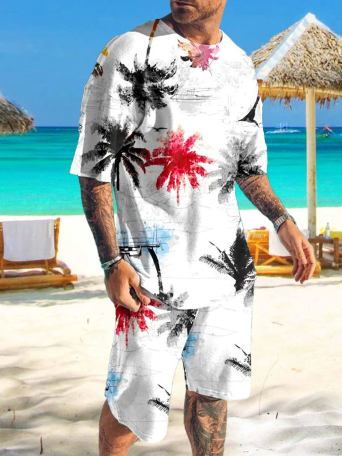 Man wearing white shirt and shorts with black and red palm tree print on a beach