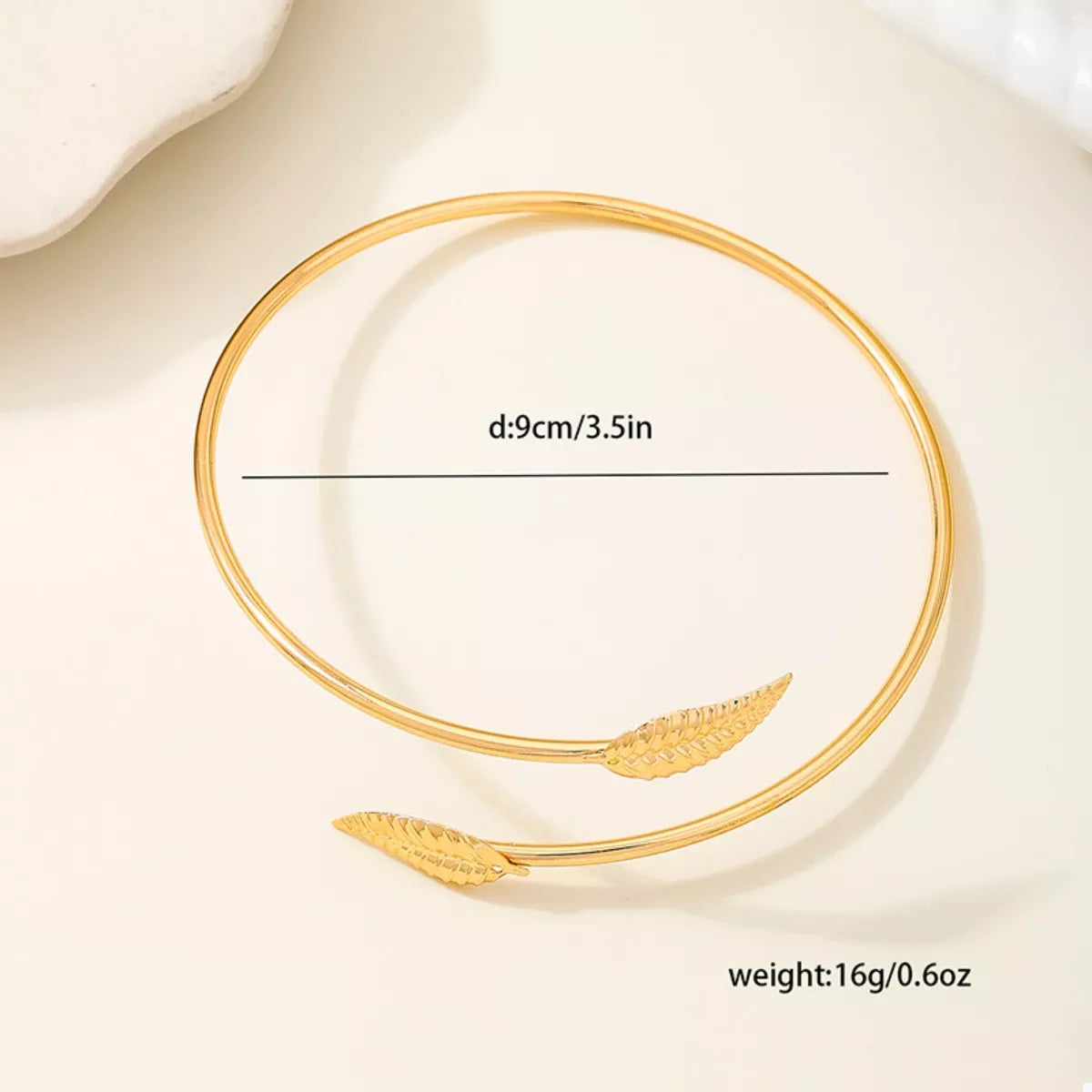 Gold-tone open leaf cuff bracelet arranged as a circle with width detail