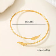 Gold-tone open leaf cuff bracelet arranged as a circle with width detail
