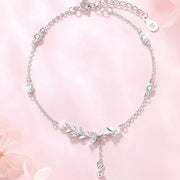 Silver leaf bracelet arranged in a circle on a pink background
