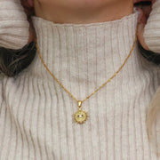 Gold-tone evil eye sunburst pendant necklace worn at the neckline