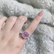 Blush pink rectangular zircon ring worn on a hand against a soft fabric background