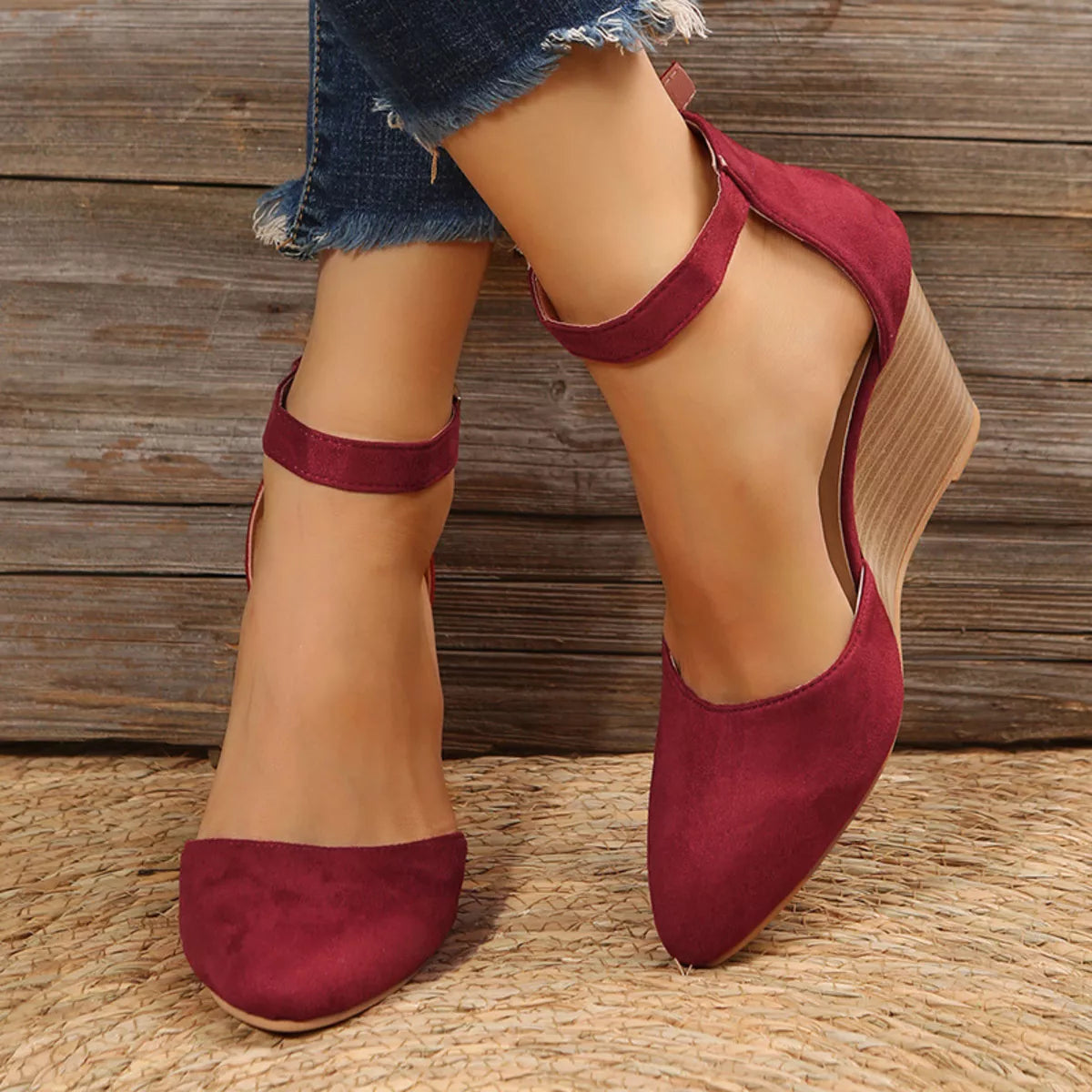 Burgundy pointed-toe wedge sandals worn with ankle straps fastened