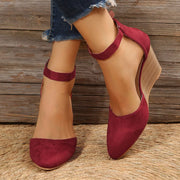 Burgundy pointed-toe wedge sandals worn with ankle straps fastened