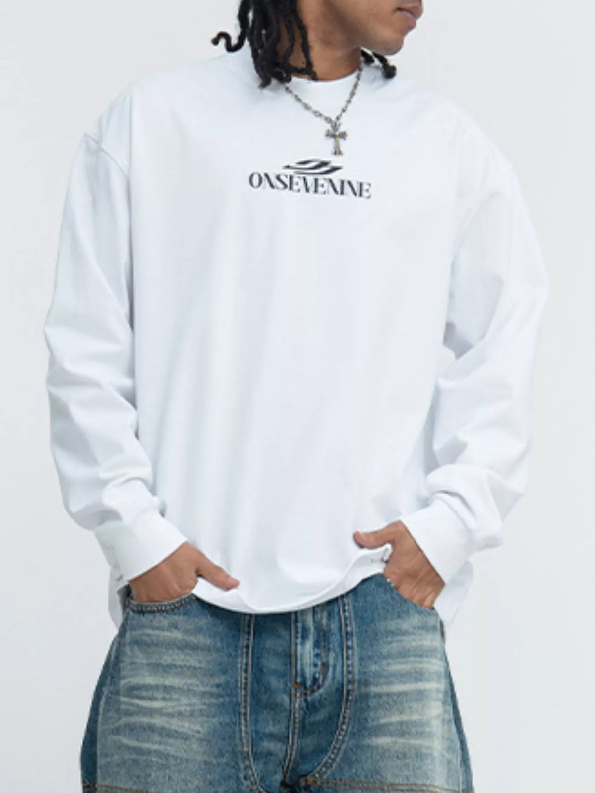 Model in a white long-sleeve tee with small dark lettering across the chest