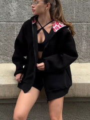 Model wearing a black zip hoodie open over a top, with red lip-print hood lining