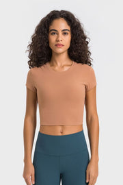 Model wearing a peach cropped T-shirt with teal leggings, front view
